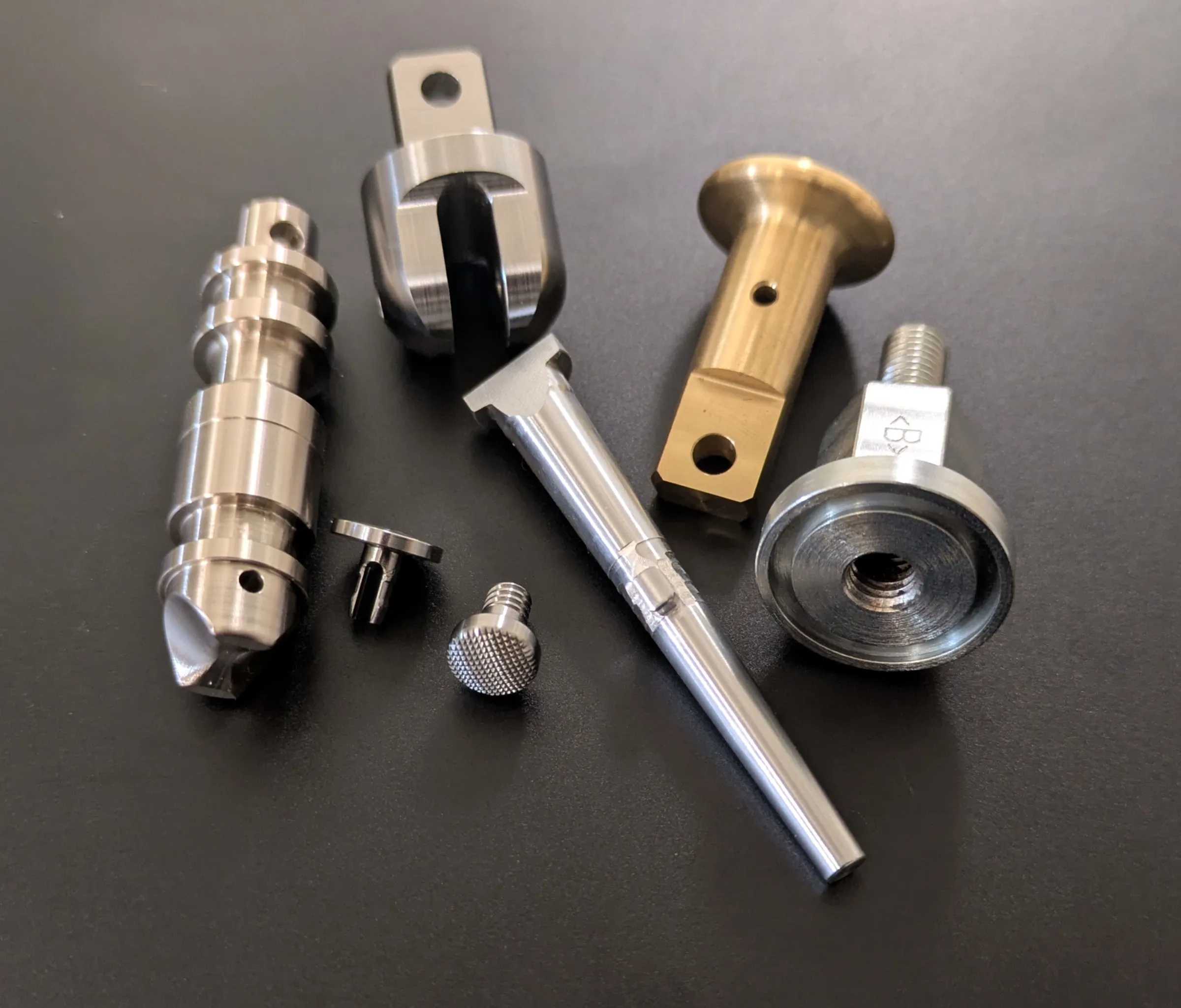 A group of machined stainless steel, brass, and aluminum parts produced by DMT Industries